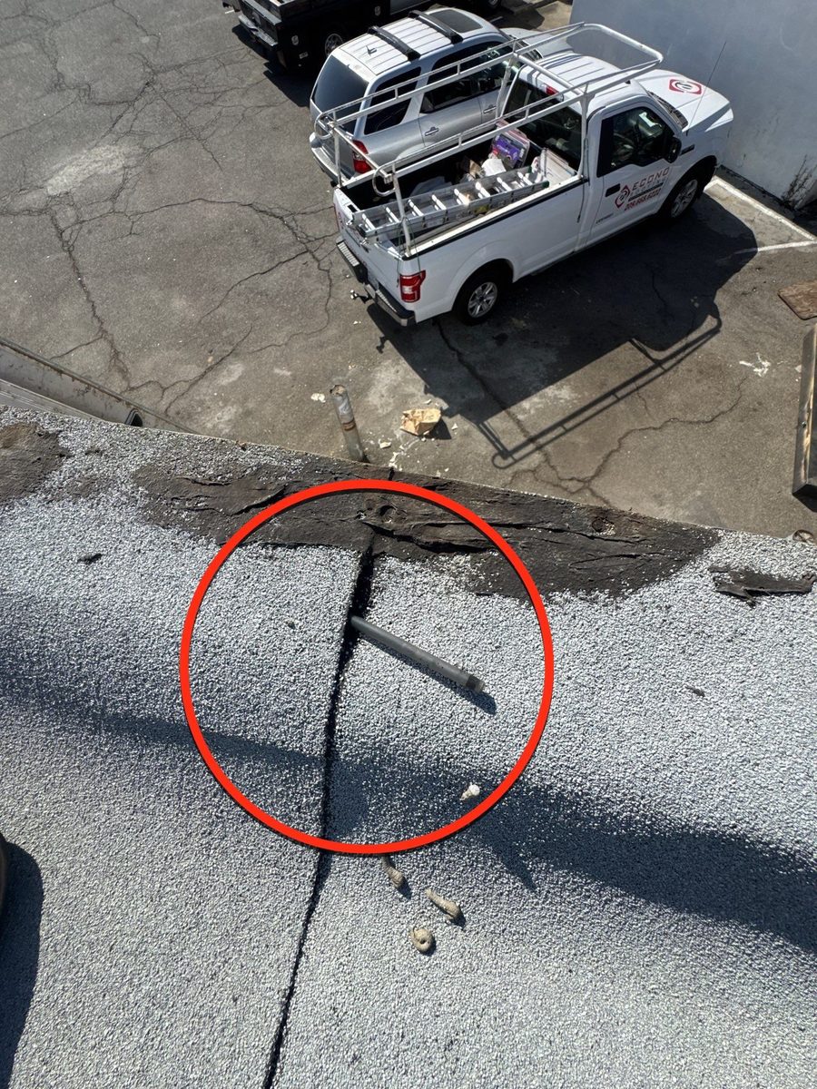Bitumen roof closeup with a protruding nail or stake circled in red — diagnostic estimate photo by Econo Roofing at Beto's Bakery Modesto.