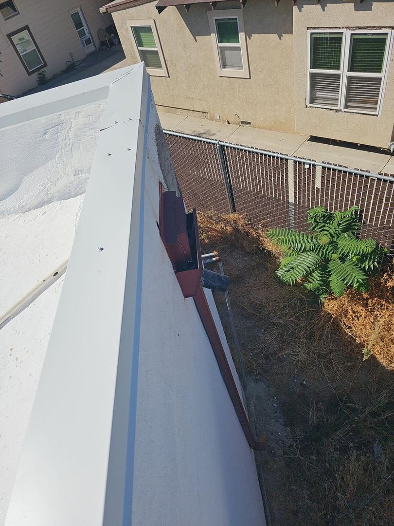 Clean edge detail with new downspout and coating edge at building perimeter