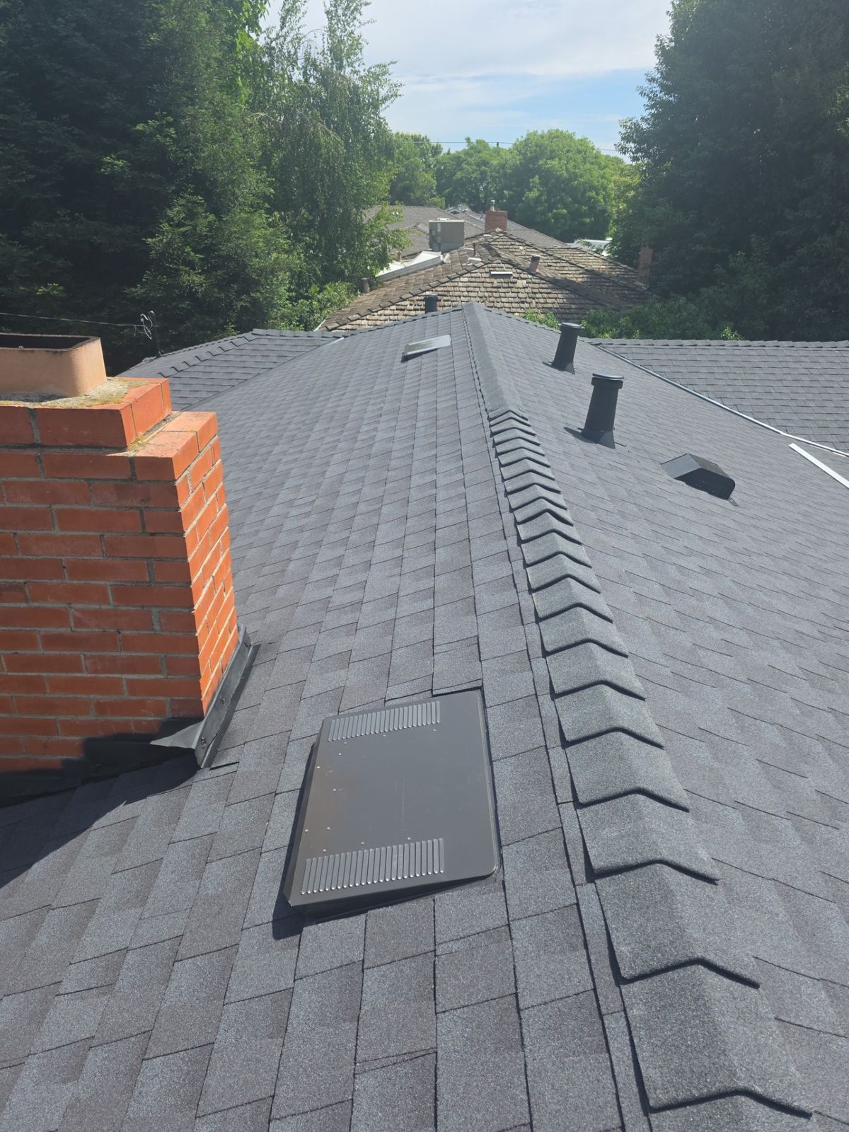 Detail of chimney with new step flashing and ridge cap on completed Turlock roof replacement
